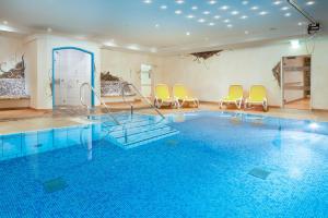 a room with a pool with chairs and a swimming pool at Ferienwohnung Poldi - Annehmlichkeiten von 4-Sterne Familien- und Wellnesshotel Viktoria können mitgenutzt werden in Oberstdorf