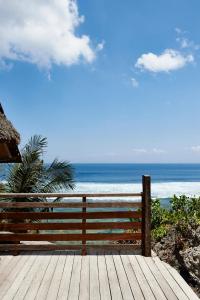 a wooden deck with a view of the ocean at The Island Houses Bingin in Uluwatu
