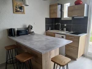 a kitchen with a counter and two stools in it at Jolie appartement refait à neuf in Saintes-Maries-de-la-Mer