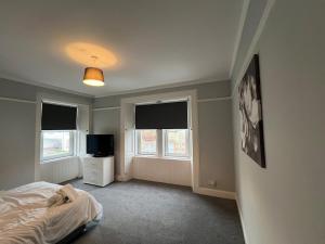 a bedroom with a bed and two windows and a television at Our Salad Days Lochgilphead in Lochgilphead