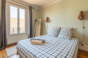 a bedroom with a blue and white bed with a window at Appartement calme avec cachet (20 min de Paris) in Maisons-Laffitte
