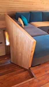 a bed in a wooden room with a blue couch at Brvnara Topilo in Niš