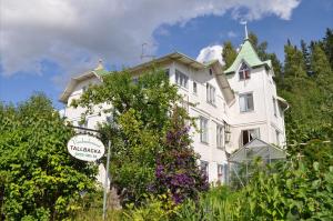 a large white house with a sign in front of it at Vandrarhemmet Tallbacka/Ängelsberg Hostel in Ängelsberg