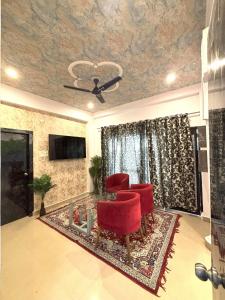 a living room with red chairs and a table at Vista Kove Flat -202 in Lucknow +7 photos