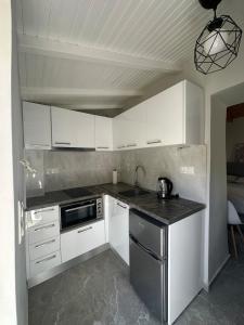 a kitchen with white cabinets and a black counter top at Mamour Apartments in Mavrovouni in Mavrovouni