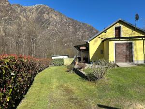 a yellow house with a mountain in the background at Ortensia casa vacanze in Antronapiana
