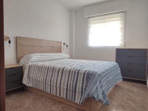 a bedroom with a bed with a striped blanket and a window at Relax on Miramar Beach in Miramar