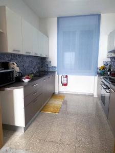 a kitchen with white cabinets and a blue window at Ambra Holiday House in Furore +9 photos