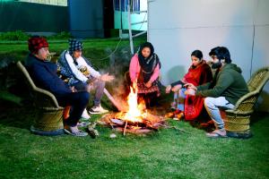 a group of people sitting around a fire at The Escapee Resort in Mussoorie