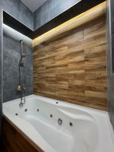 y baño con bañera blanca y pared de madera. en Elite Center Apartment, en Oradea