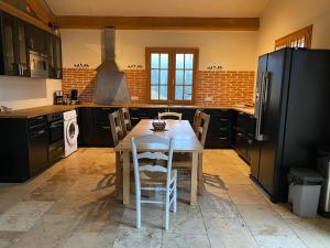 a kitchen with a wooden table and a black refrigerator at Les 3 flocons in La Colmiane