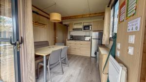a small kitchen with a table and chairs in a caravan at Camping Onlycamp le Champ d'été in Reyssouze