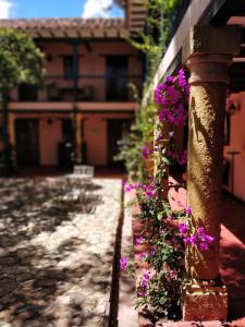 a stone wall with purple flowers on a house at Hotel Plazuela de San Agustín - PSA Hotel in Villa de Leyva