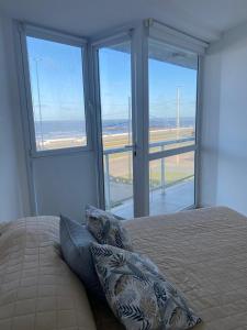a bedroom with a bed with pillows in front of windows at Vista Linda in Mar del Plata