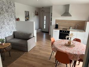 eine Küche und ein Wohnzimmer mit einem Tisch und einer Couch in der Unterkunft Maison de campagne proche 24h in Roézé-sur-Sarthe