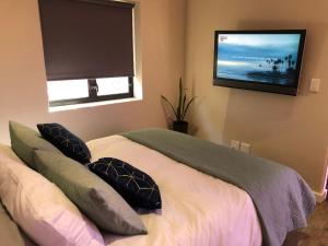 a bedroom with a bed with pillows and a flat screen tv at Modern, Comfy Guest Suite with Beautiful Views in Tygerberg Hills
