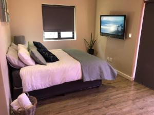 a bedroom with a bed with a tv on the wall at Modern, Comfy Guest Suite with Beautiful Views in Tygerberg Hills