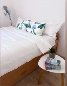 a bed with white sheets and a table with a book at Casa Nina Fruška gora in Maradik