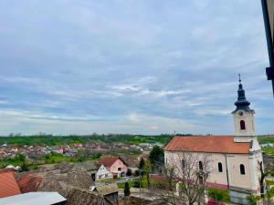 una iglesia con una torre de reloj en la cima de una ciudad en Wine story, en Irig
