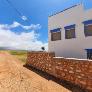 a building with a stone wall next to a dirt road at tamazirt surf in Agadir