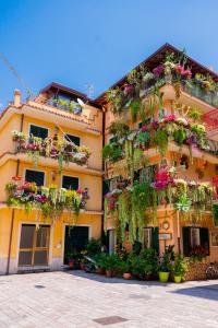 a yellow building with lots of plants and flowers at Appartamenti Paolone House Taormina Mare in Mazzeo