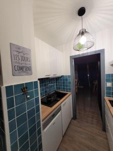 eine Küche mit blau gefliesten Wänden und einer Spüle in der Unterkunft Studio avec balcon sud LES PISTEURS in Le Dévoluy + 3 Fotos