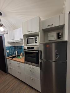 eine Küche mit einem Kühlschrank aus Edelstahl und einer Mikrowelle in der Unterkunft Studio avec balcon sud LES PISTEURS in Le Dévoluy