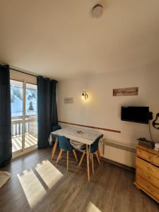 ein Esszimmer mit Tisch und Stühlen und einem Fernseher in der Unterkunft Studio avec balcon sud LES PISTEURS in Le Dévoluy