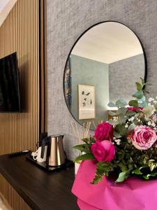 a vanity with a mirror and a bouquet of pink roses at Villa Riviera Hotel Udine in Pradamano