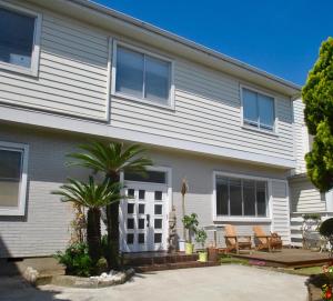 une maison blanche avec un palmier en face dans l'établissement 女性専用 Inn By The Sea Kamakura - Women's Guesthouse, à Kamakura