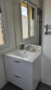 ein weißes Badezimmer mit Waschbecken und Spiegel in der Unterkunft Le "Chic en Ville" Centre historique, climatisé, wifi, Parking sous-sol inclus in Bergerac + 26 Fotos