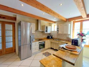 a kitchen with white cabinets and a stainless steel refrigerator at Gite de Kerantum in Mahalon