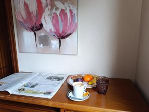 a table with a newspaper and a cup of coffee and fruit at Pensión Prieto in Junquera de Espadañedo