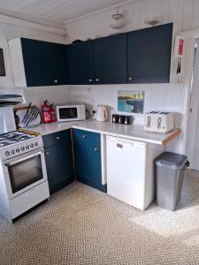 a kitchen with blue cabinets and white appliances at 2 bedroom chalet bungalow on Humberston Fitties. in Humberston +16 photos