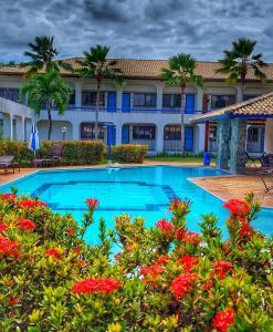 een resort met een groot zwembad met rode bloemen bij Guarajuba Summer Flat in Guarajuba