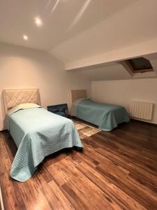 Un dormitorio con dos camas y suelo de madera. en Appart Magnifique 2 chambres, en Molinges