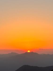 a sunset over the mountains with the sun setting on the horizon at The Tatwa Hotel & Camping in Chakrāta