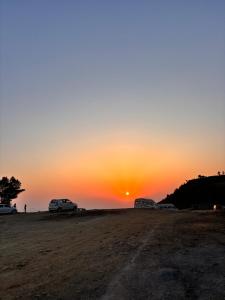 two cars parked on a dirt road at sunset at The Tatwa Hotel & Camping in Chakrāta