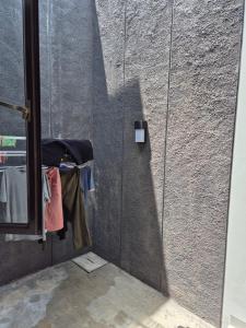 a sliding glass door with a clothes rack next to a wall at Wima homestay batu in Batu
