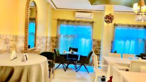 a dining room with tables and chairs and blue curtains at BEST HOTEL Aero-Batignoll in Brazzaville