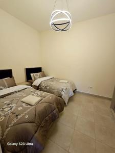 a bedroom with two beds and a chandelier at C32 Samarah Resort LOFT apartment in Sowayma
