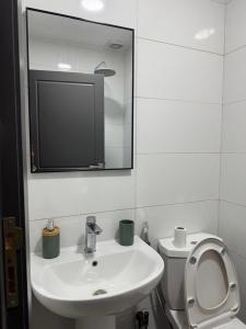 Un baño con lavabo, inodoro y espejo. en Le cosy F3 de Ouakam, en Dakar 5 fotos más
