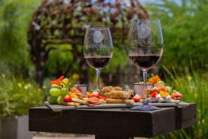 two glasses of wine sitting on a table with food at OJO AZUL RESORT in Valle de Guadalupe