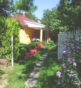 a garden with a house with a fence and flowers at La Dolche Villa in Szőlősgyörök +13 photos