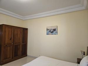 a bedroom with a bed and a wooden cabinet at Keur Aïda Immeuble de standing in Dakar