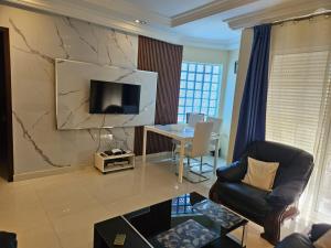 a living room with a table and a tv on a wall at Keur Aïda Immeuble de standing in Dakar