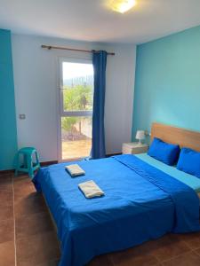 ラ・オリーバにあるBlue Wave House Corralejoの青いベッドルーム(青いシーツと窓付きのベッド付)