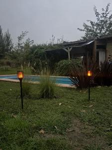two lights in the grass in front of a house at Gentil Morada in Villa Yacanto