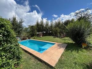 a swimming pool in a yard with grass and trees at Gentil Morada in Villa Yacanto