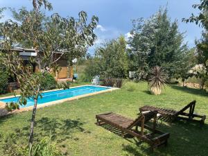 a backyard with a pool and a wooden bench at Gentil Morada in Villa Yacanto